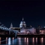 Night photo showing the Millennium Bridge leading to the Thames riverside and buildings in front of St Paul's Cathedral Dome.