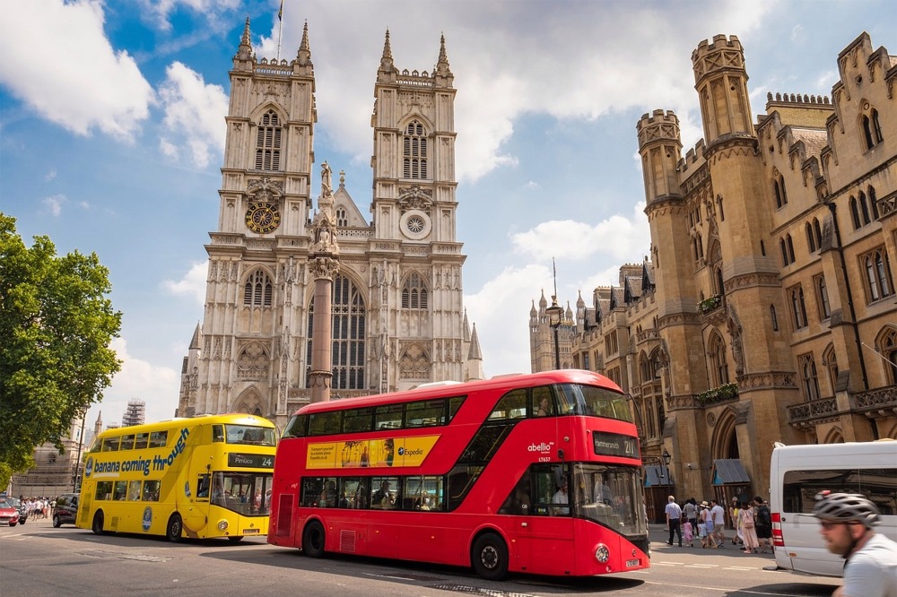 Two busses and many people outside Westminster Abbey.