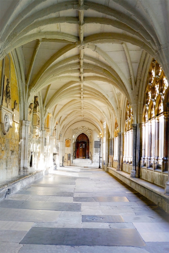 The elaborate gothic architecture, the ribbed vaulted ceiling and the flagstones of a cloister at Westminster Abbey in London.